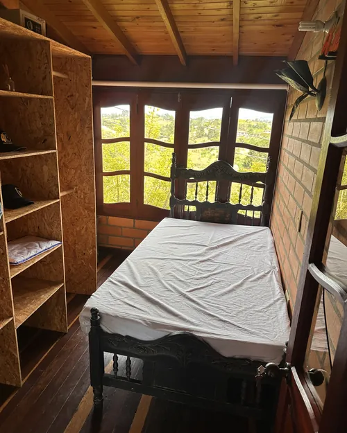 Habitación bajo el techo de madera con repisas de madera y ventanal al campo