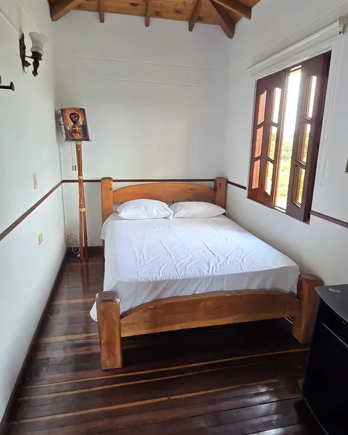 Habitación con cama de madera curva y ventanal de vidrios de colores